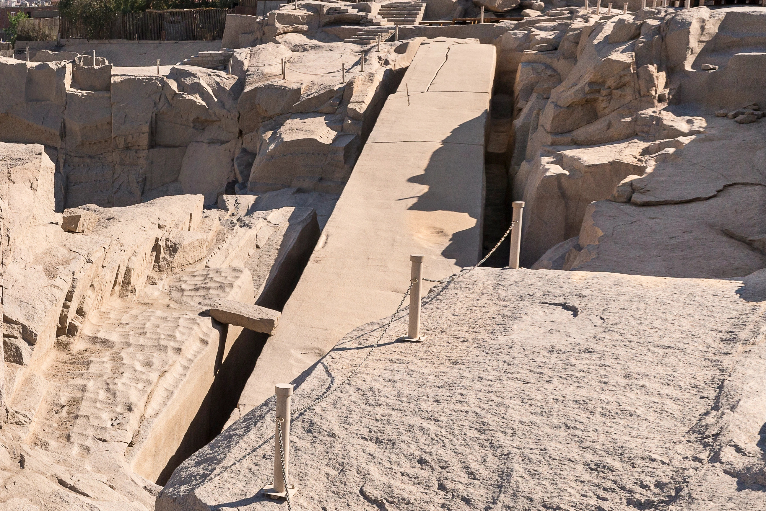 L’obélisque inachevé d’Assouan encore solidaire de la roche mère, entre deux tranchées, avec des fissures visibles.